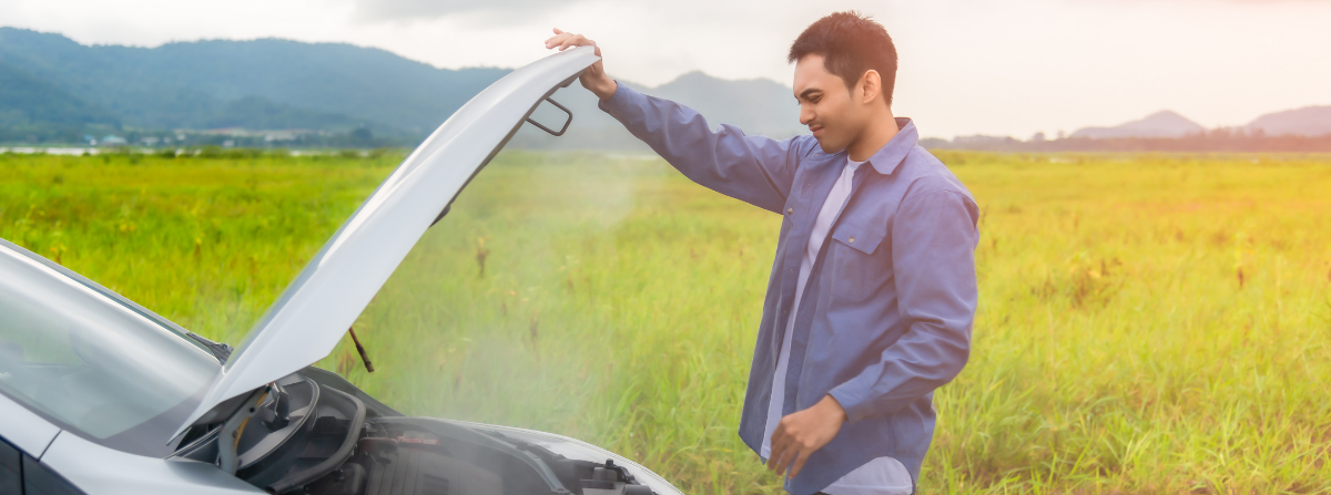 man standing over an overheating car